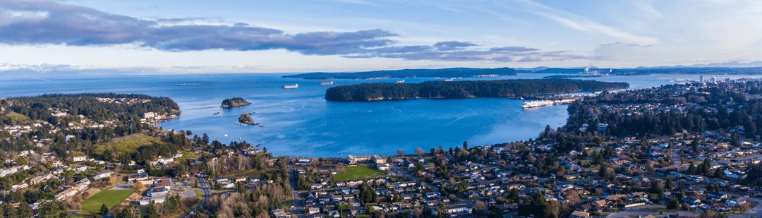 A panoramic view across Departure Bay, its shoreline homes and wooded islands