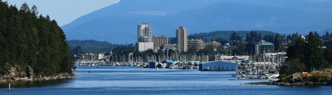 Nanaimo’s harbour and skyline seen across the water, with mountains behind
